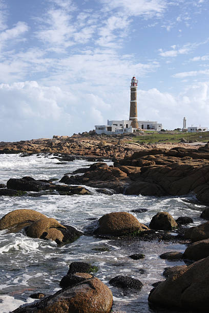 Lighthouse at the ocean coast with waves crashing on rocks Lighthouse of Cabo Polonio in a sunny afternoon. cabo polonio photos stock pictures, royalty-free photos & images