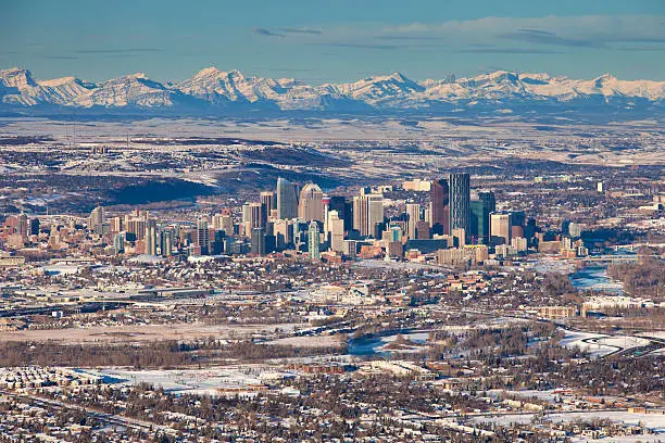 Aerial photo of the downtown Calgary skyline with the majestic Canadian Rockies in the background.