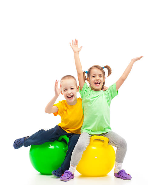 dos niños saltando heaving fiesta con bola - bouncing ball family playing fotografías e imágenes de stock