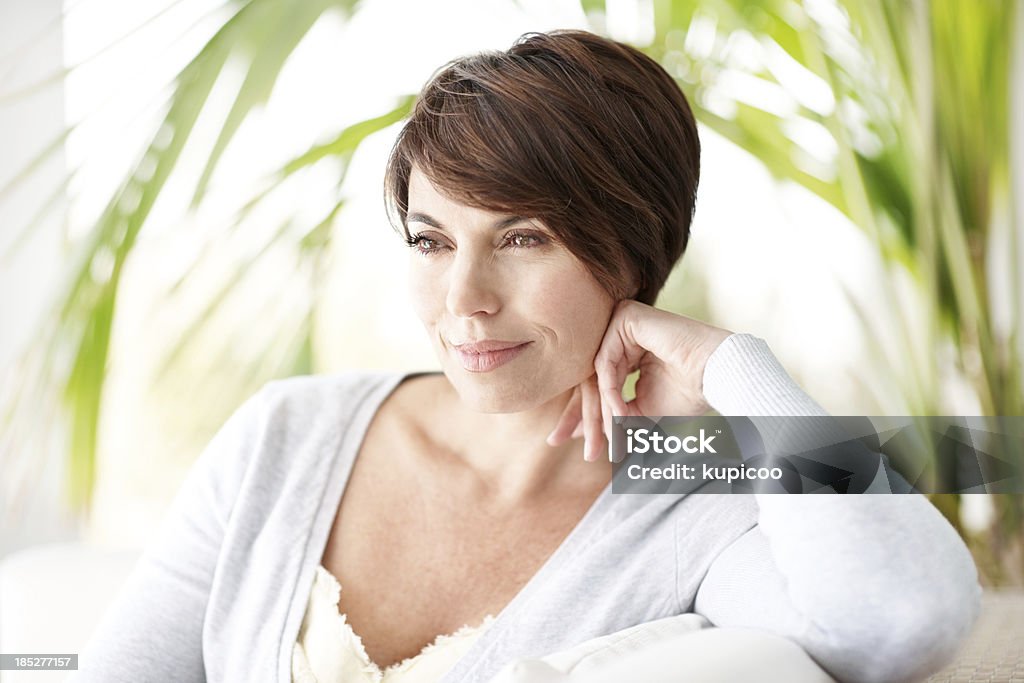 Woman smiling and resting head on hand Lovely brunette stares dreamily while relaxing on sofa - copyspace Adult Stock Photo