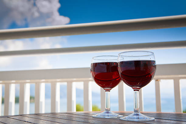 two glasses of red wine on balcony with seaview