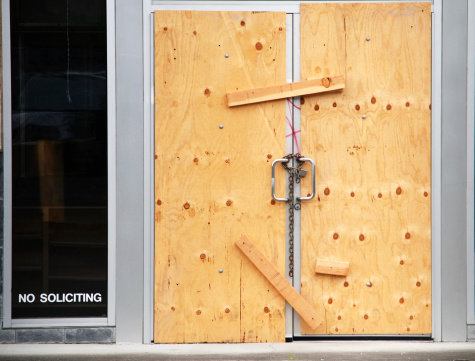 Boarded up doors of business closed with lock and chain