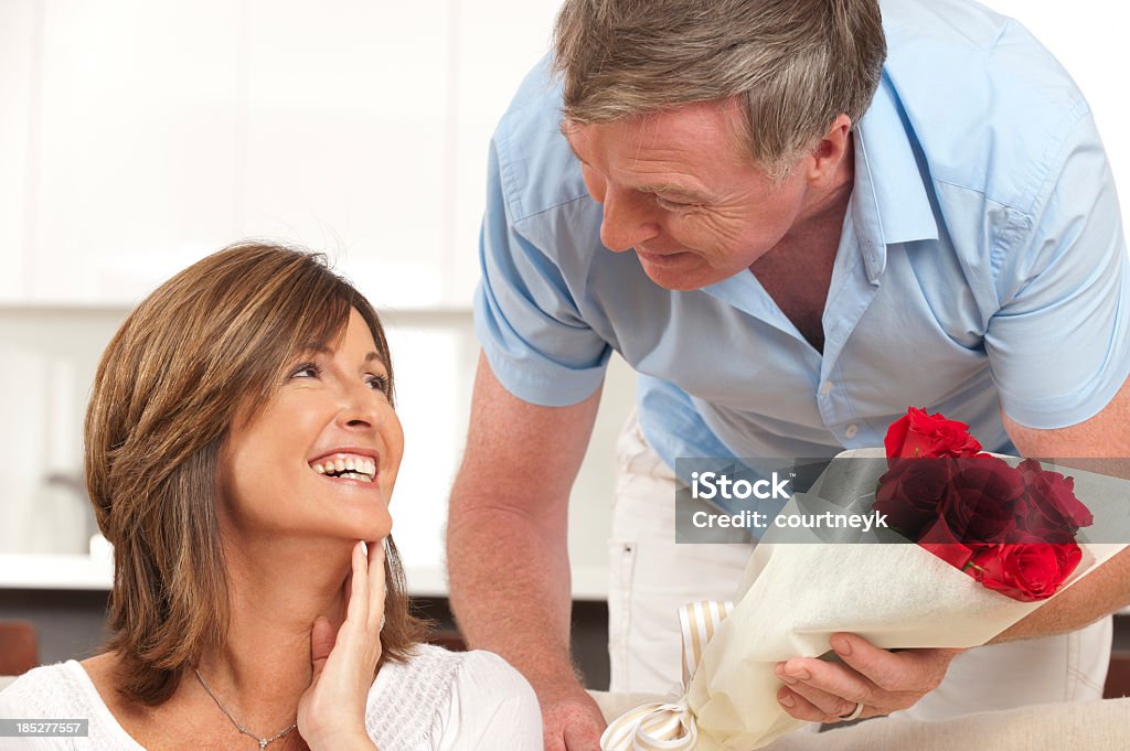 Hombre feliz dando a su esposa rosas - Foto de stock de 40-44 años libre de derechos
