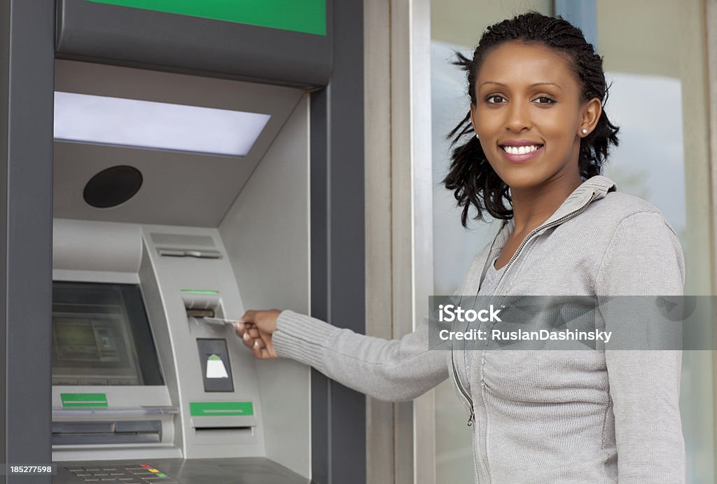 Withdraw cash money. Casual young woman withdrawing money from  an ATM machine. ATM Stock Photo