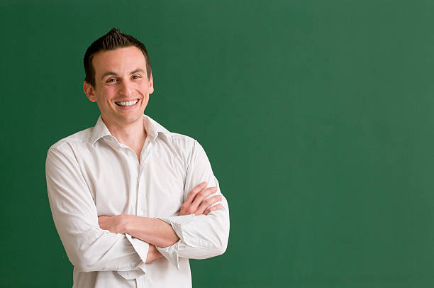 istock teacher with arms crossed at blackboard 185277707