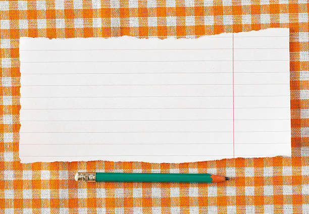 istock Pencil and paper on orange tableclot 185277769