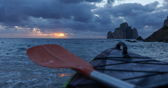 Wild beach, inflatable kayak and storm clouds
