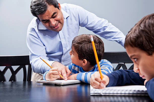 latina-padre di aiutare i bambini con attività - looking over shoulder looking men looking up foto e immagini stock