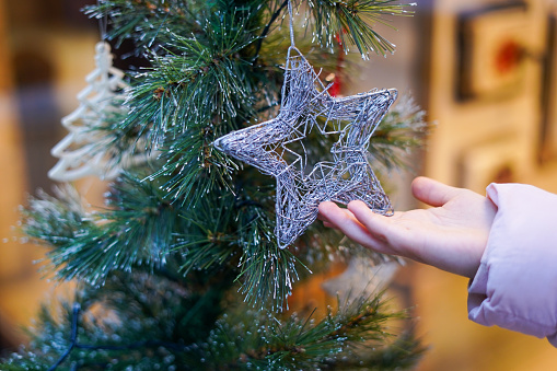 Christmas silver star in the hand of little girl. Child holding Christmas ornament outdoors