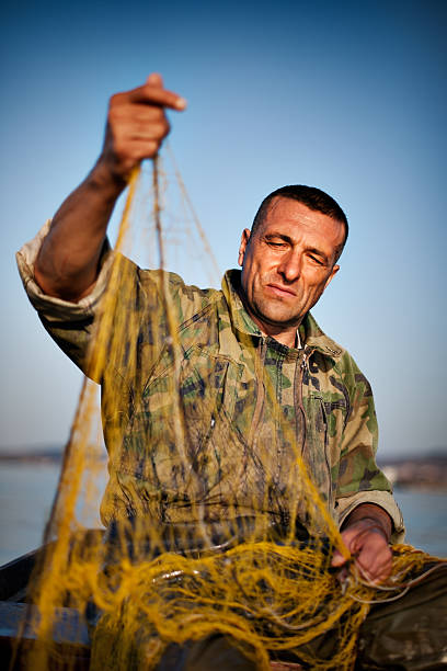 Fisherman in his river boat holding a yellow fishing net.