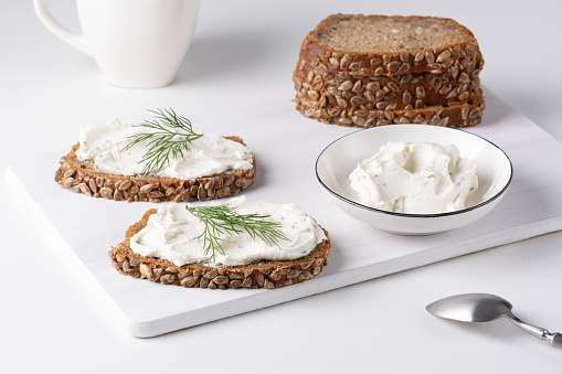 Rye bread with cream cheese and dill on a white table. Whole grain rye bread with seeds.