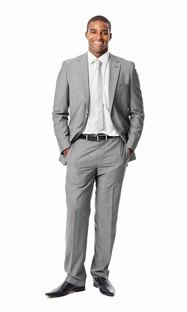 Businessman With Hands In Pockets - Isolated Full length portrait of a confident African American businessman smiling with hands in pockets. Vertical shot. Isolated on white. hands in pockets stock pictures, royalty-free photos & images