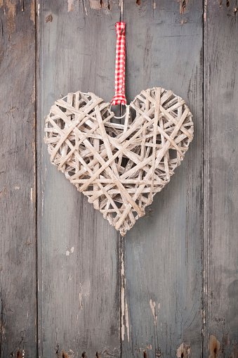 Wicker heart shape on rustic weathered door. 