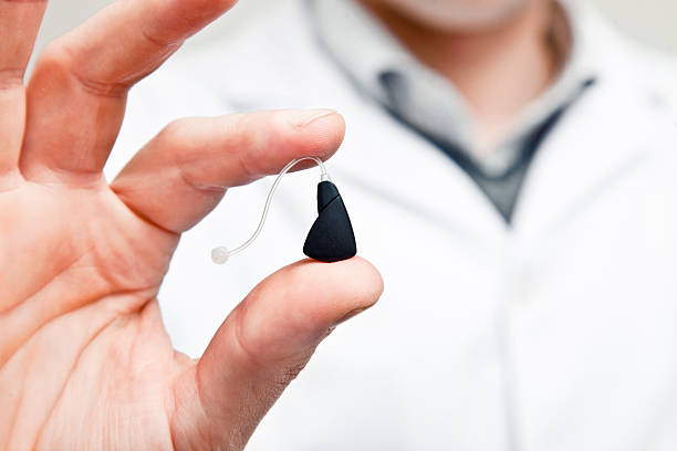 Las generation hearing aid Doctor holding a last generation hearing aid.More hearing and Ear health related files at: ear horn photos stock pictures, royalty-free photos & images