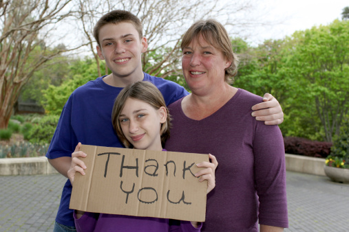 Family holding a Thank You sign.