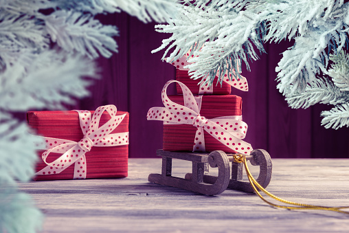 Red gift boxes on Santaâs sleigh framed by frosty Christmas tree branches. New Year and Xmas greeting card