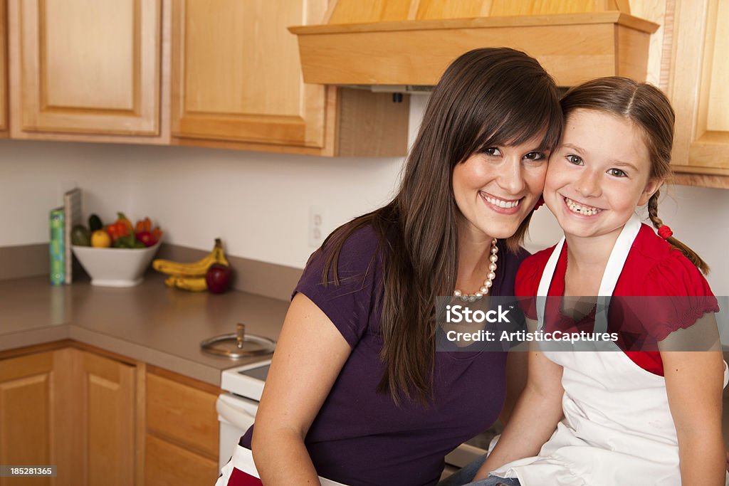 Happy Young Mother and Her Daughter in the Kitchen Together "Color image of a happy, young mom, and her daughter in the kitchen of their home." 25-29 Years Stock Photo