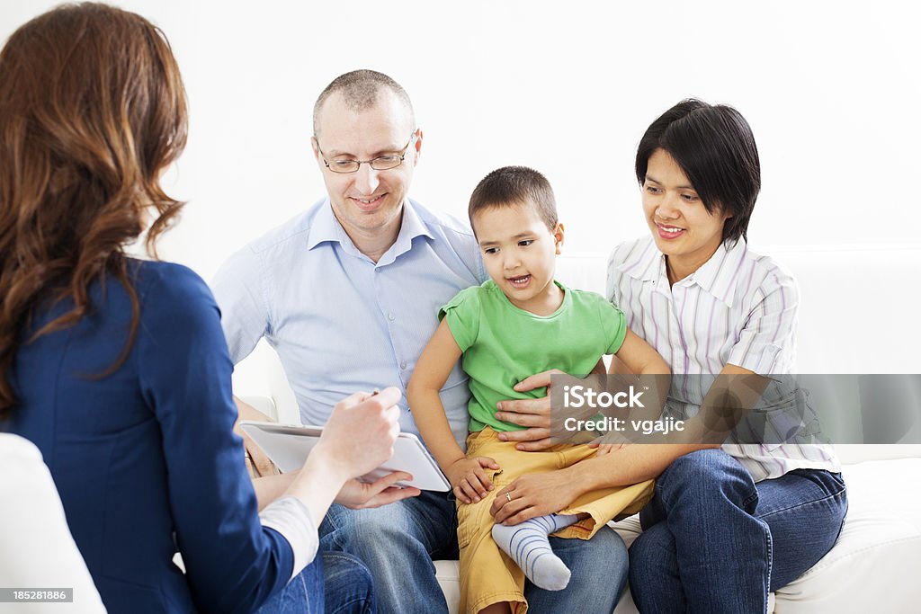 Mixed Race Family Meeting With Financial Advisor Mixed Race Family with two children meeting With Financial Advisor presenting new bank offers and investments on digital tablet PC. Businesswoman pointing with pen to some new offers on a digital tablet PC. Family Stock Photo