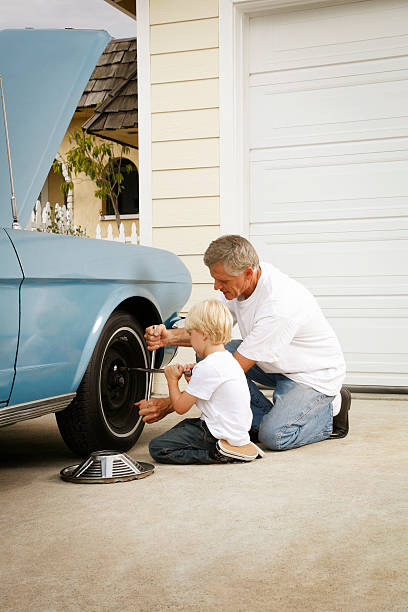Father and Son Working on the Car This is a photo of a 4 year old boy and 50 year old man changing the tire on a 1967 Ford Mustang.click on the links below to view lightboxes. collectors car photos stock pictures, royalty-free photos & images