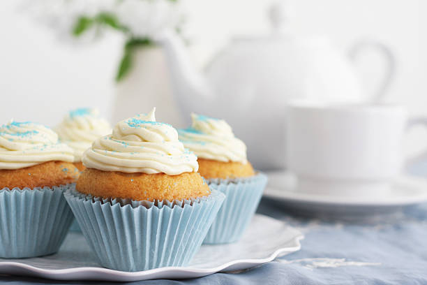 Four cupcakes with white icing and tea stock photo
