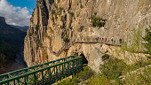 Bridge or walkway with a large group of unrecognizable people over a rock wall in the exit canyon of the Caminito del Rey