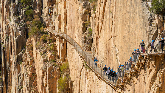 Puente o pasarela con grupo grande de personas irreconocible sobre una pared de roca en el cañón de salida del Caminito del Rey