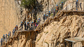 Bridge or walkway with a large group of unrecognizable people over a rock wall in the exit canyon of the Caminito del Rey