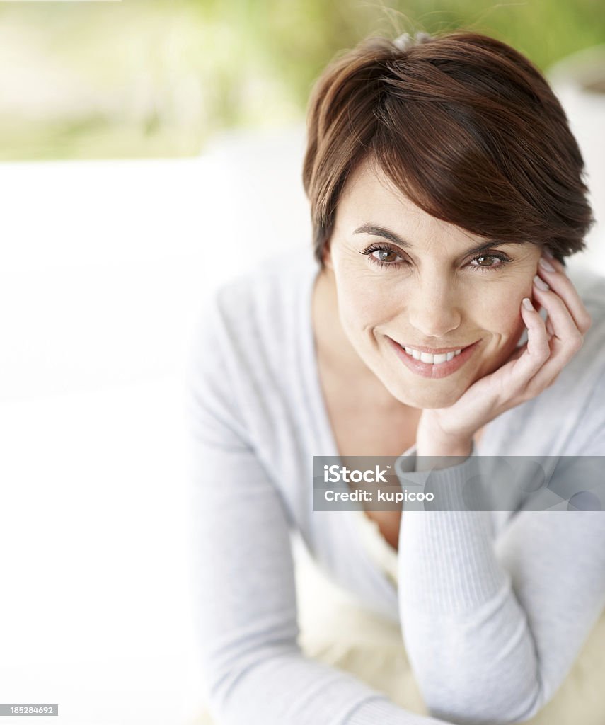Positivity is my secret weapon Close-up of lovely brunette smiling at the camera with her chin resting in her palm Chin Stock Photo
