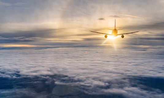 Flying over clouds at sunrise is a commercial aircraft carrying passengers. notion of business, leisure, and quick travel.