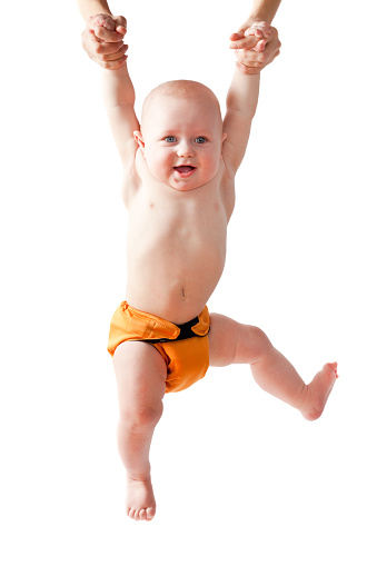 Caucasian baby boy wearing a durable cloth diaper hanging on air from his mother's hands isolated on white background.