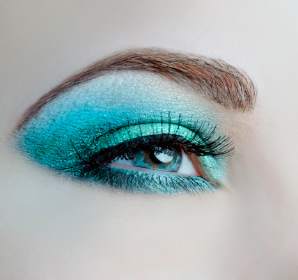 woman blue eyes macro shoot with turquoise make-up.