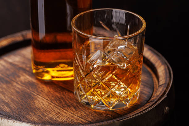 istock Whiskey glass with ice on a rustic barrel, a classic sip 1852862800