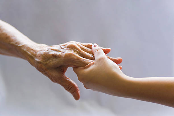 aiutando a mano - holding hands human hand senior adult consoling foto e immagini stock