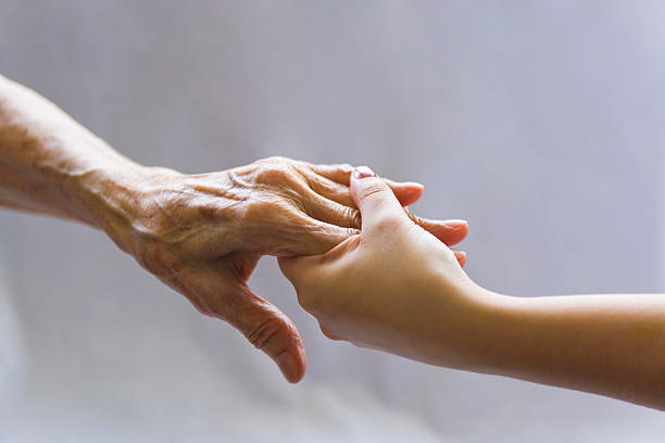 Young hand reaching out to a elderly persons hand Young woman is holding a senior woman's  hand for help. old hands stock pictures, royalty-free photos & images