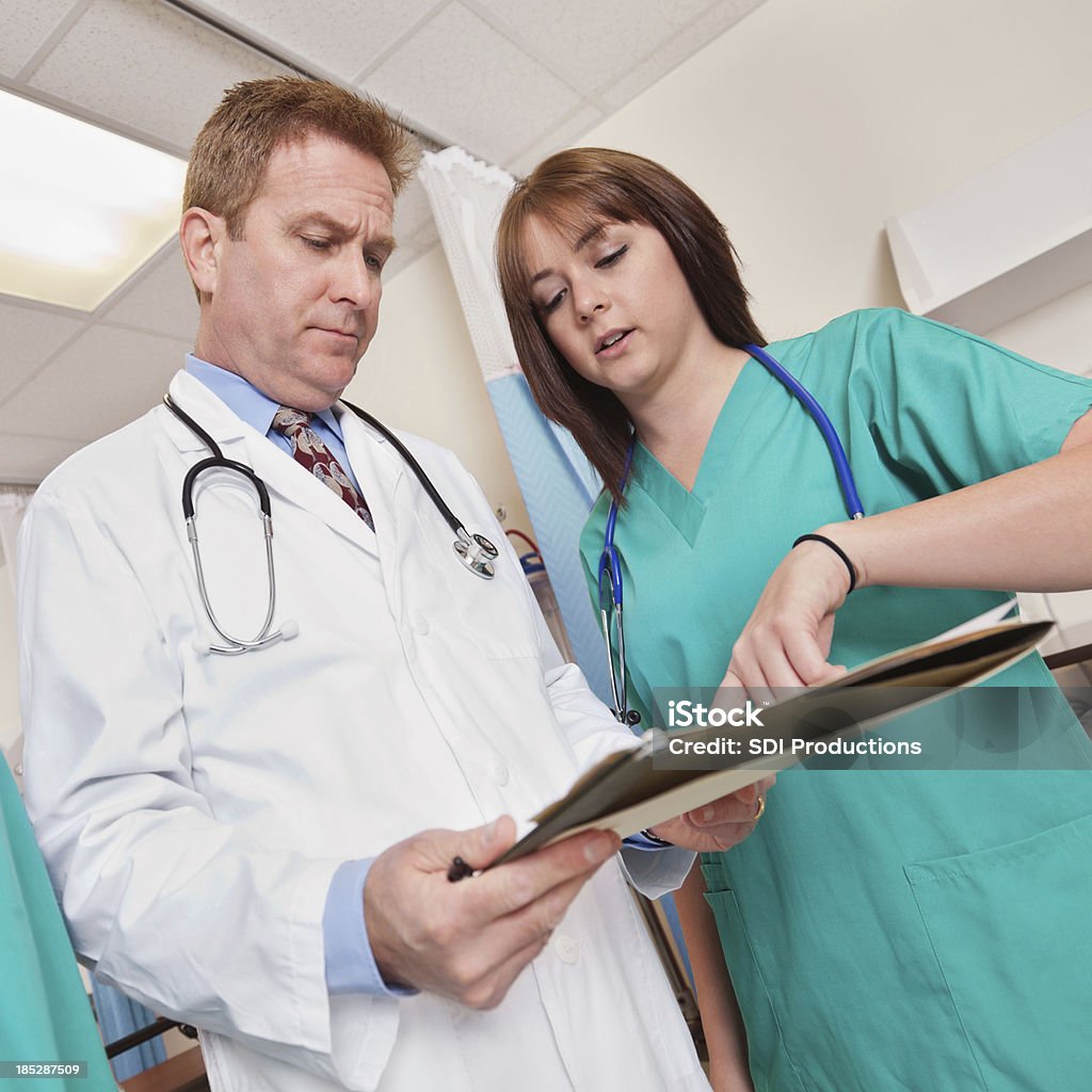 Arzt und Krankenschwester diskutieren im Krankenhaus Patienten Diagramm - Lizenzfrei Arbeiten Stock-Foto