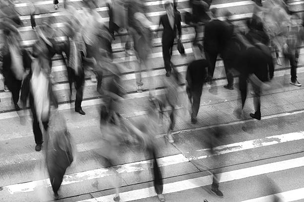 Commuters Crossing Street "Crowd of people crossing the street, black and white, high angle view and defocused." rat race stock pictures, royalty-free photos & images