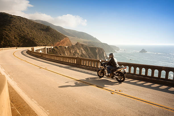 мотоцикл пересеките мост биксби, big sur, калифорния, сша - cliff sea coastline beach стоковые фото и изображения