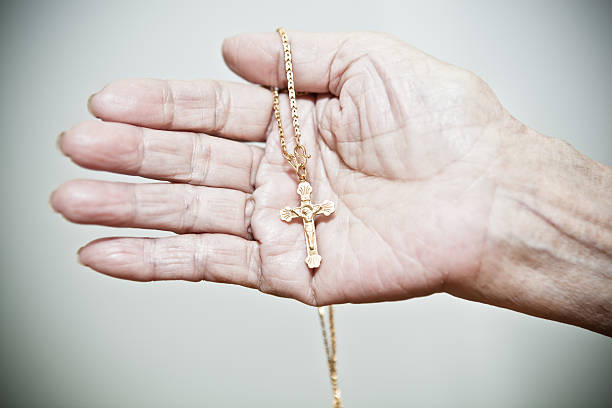 istock Old woman holding gold crucifix in hand 185288079