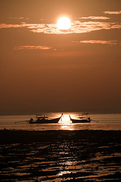 longtail barcos flutua no receeding mar ao pôr do sol - receeding - fotografias e filmes do acervo