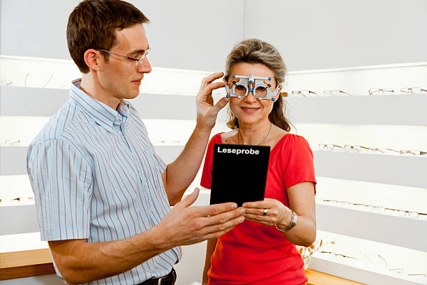 testing eye glasses optometrist and woman checking glasses for reading- german word on board means reading test Messbrille stock pictures, royalty-free photos & images