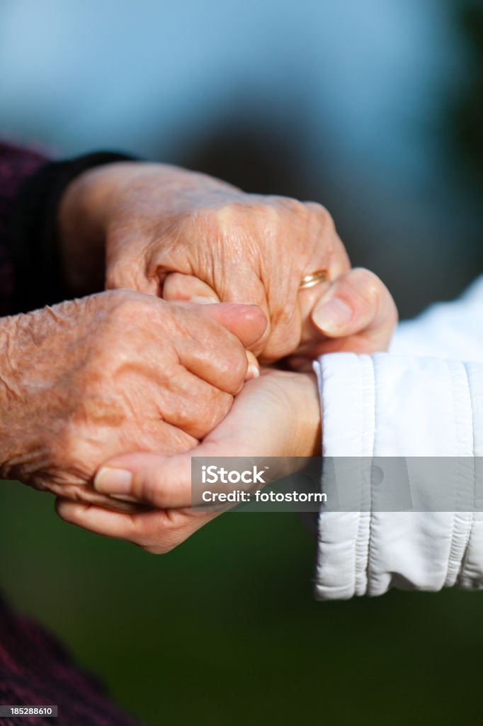 Jovem e uma mulher sênior, segurando as mãos - Foto de stock de Assistência royalty-free