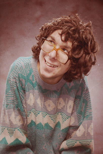 Nerd Young Man 1980s Yearbook Photo "A nervous nerdy teenager with bad 1980s sweater and glasses, looks shy as he poses for his high school portrait freshman year.  Soft faux marble background.  Vertical.  INTENTIONAL DEGRADATION OF IMAGE AND LIGHTING FOR VINTAGE FEEL." high school photos stock pictures, royalty-free photos & images