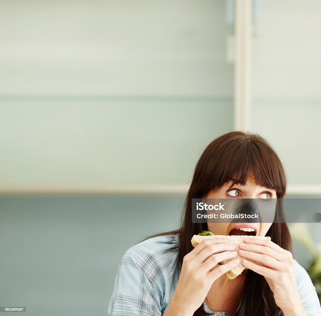 Girl having mouth open wide and munching a sandwich Pretty brunette woman about to take a big bite out of her sandwich  - Copyspace Sandwich Stock Photo