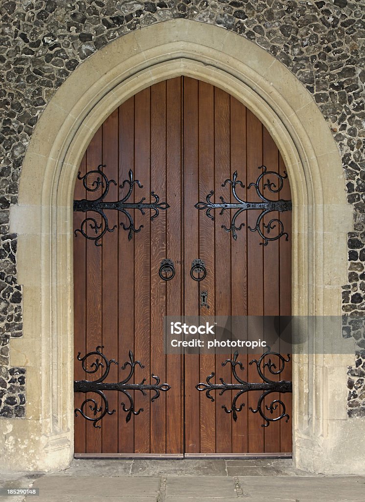 beautiful church door "a beautiful door from a church which has origins in the 15th Century. Set in a sandstone arch which is surrounded by flint clad walls, the finely crafted oak doors are hinged with ornate ironwork." Door Stock Photo