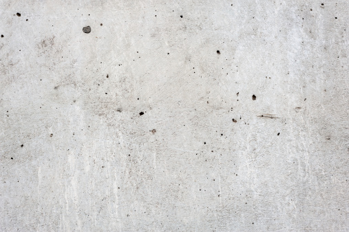 Grungy concrete wall with black paint spatter. Soft lighting with excellent detail.