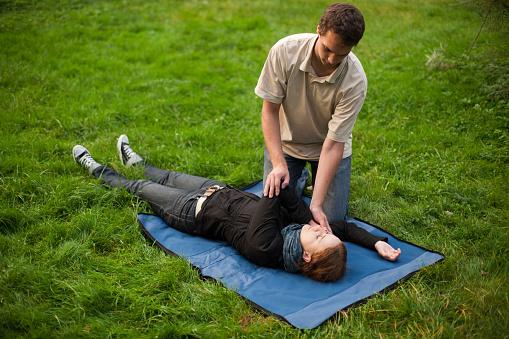 Man performing first aid on a girl. On the grass