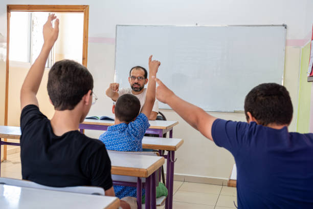 Students raising their hands to answer the teacher question