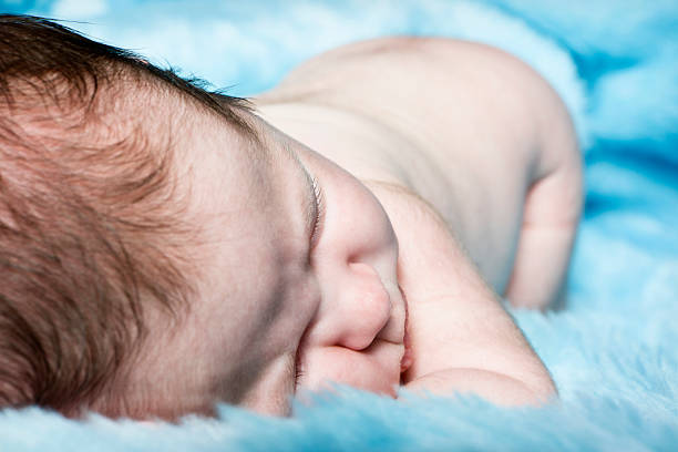 blick auf baby junge schlafen auf blaue decke - fake fur white happiness beginnings stock-fotos und bilder