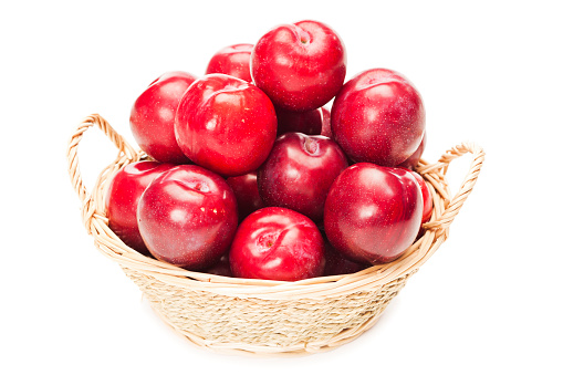 Red plums inside basket
