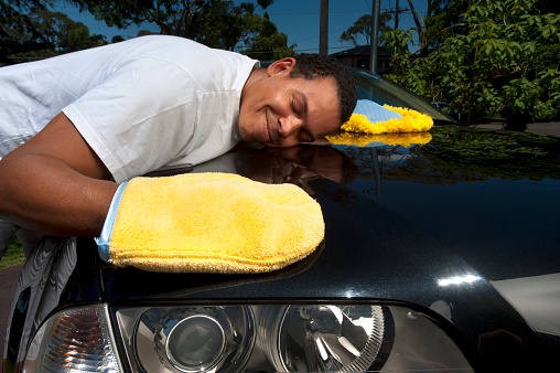 Man carefully polishing his car with polishing gloves